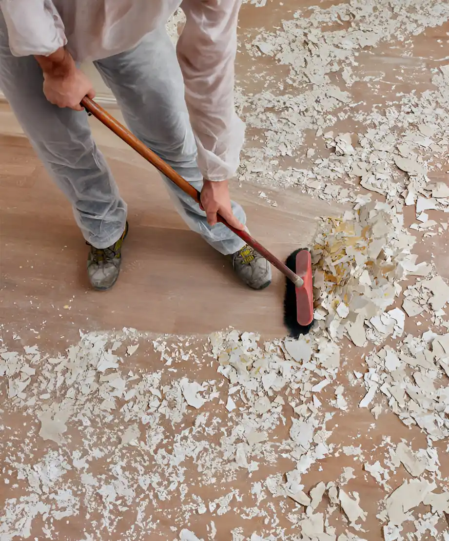 Arbeiter beim Fegen von Bauschutt von einem Holzboden mit einem Besen in Reutlingen