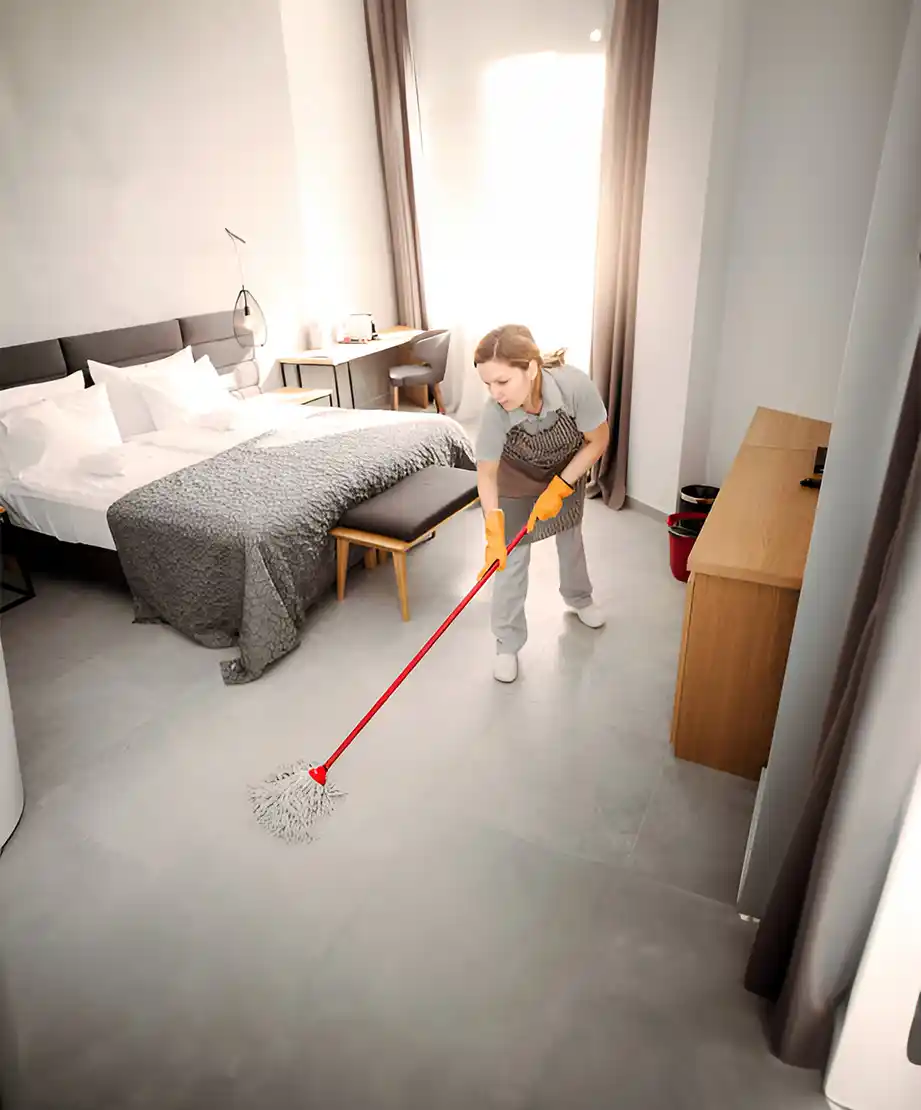 Haushälterin wischt den Boden in einem modernen Hotelzimmer