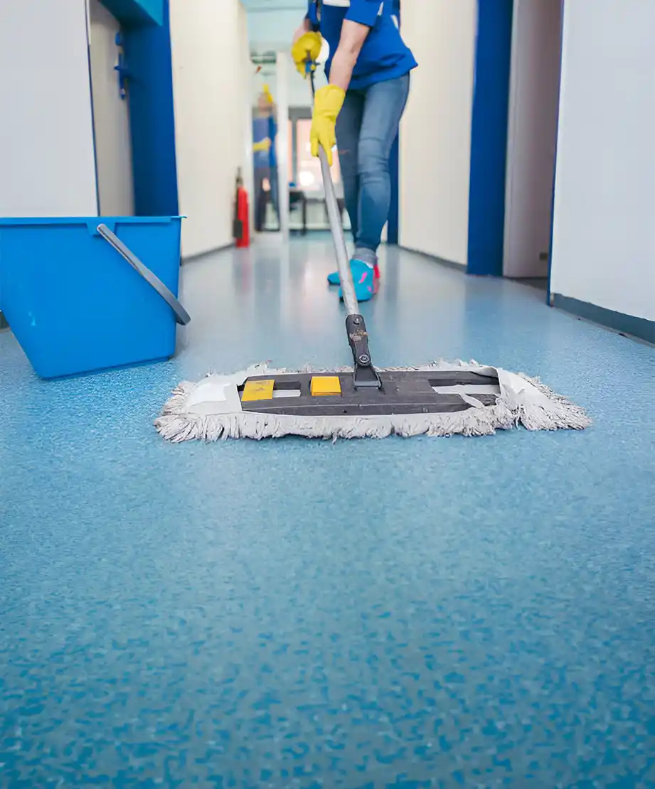 Arbeiter wischt einen blauen Flurboden mit einem Eimer und gelben Handschuhen in Reutlingen