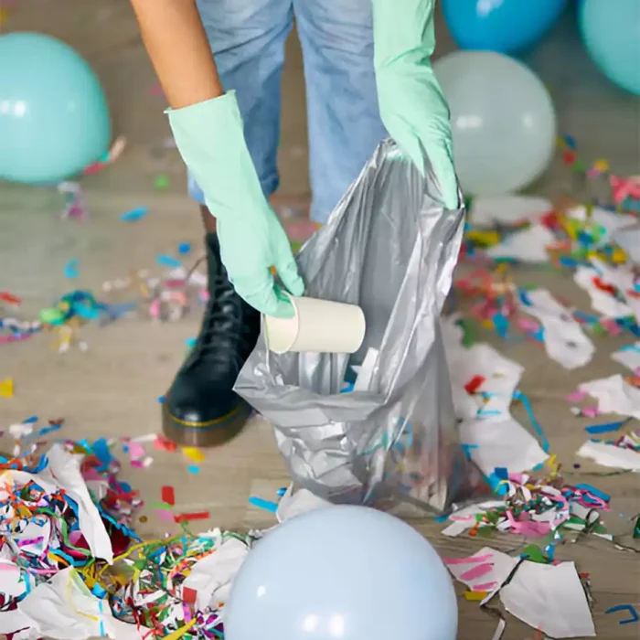 Hände mit Handschuhen, die Partyabfälle wie Becher und Luftballons in einem Müllsack auffangen in Coswig