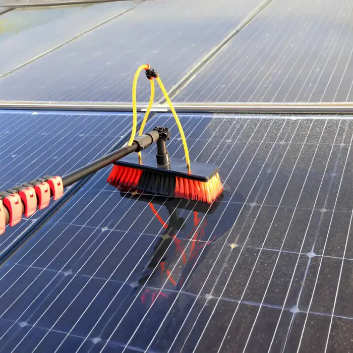 Nahaufnahme einer Bürste zur Reinigung eines Solarmoduls mit angeschlossenen Wasserschläuchen
