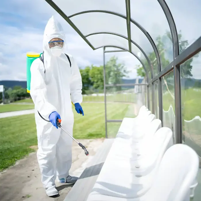Arbeiter im Schutzanzug bei der Desinfektion einer Stadionbank mit einem Sprühgerät in Reutlingen
