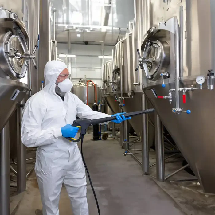 Arbeiter in voller Schutzausrüstung bei der Desinfektion von Ausrüstung in einer Brauerei in Sinsheim