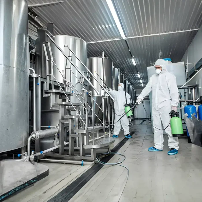 Arbeiter in Schutzanzügen desinfizieren große Tanks in einer Fabrik in Recklinghausen