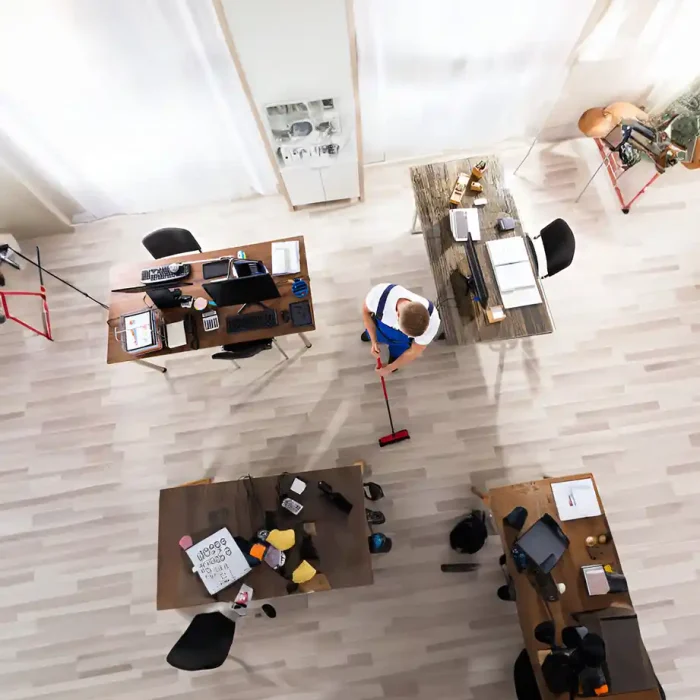 Draufsicht auf einen Arbeiter, der ein modernes Büro mit Schreibtischen und Stühlen reinigt in Reutlingen