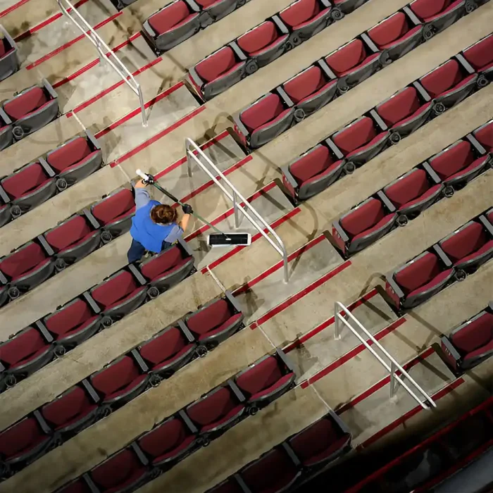 Ein Arbeiter reinigt zwischen den Sitzreihen in einem Theater, von oben gesehen in Aschaffenburg