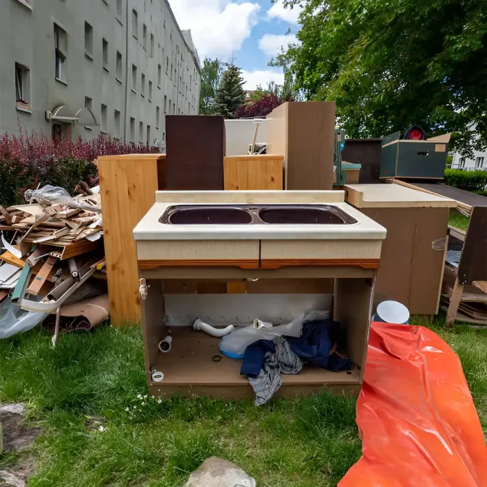 Alter Küchenschrank und Schutt auf der Wiese vor einem Wohnhaus entsorgt