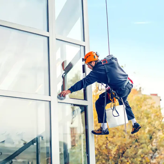Arbeiter mit Schutzausrüstung bei der Reinigung großer Fenster an der Außenseite eines Gebäudes in Reutlingen