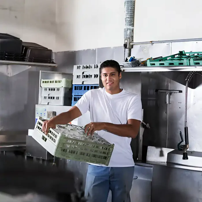 Arbeiter, der ein Geschirrregal in einer Großküche aus Edelstahl handhabt in Reutlingen