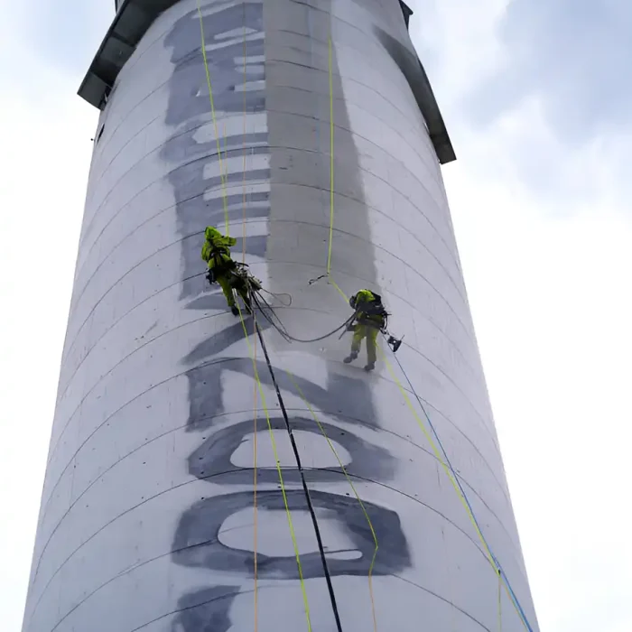 Arbeiter verwenden Seilzugangstechniken, um Graffiti von einem großen Turm zu entfernen in Albstadt