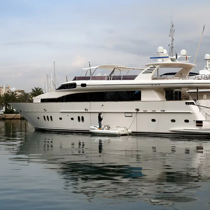 Eine große Yacht, die auf ruhigem Wasser vertäut ist und auf deren Deck eine Person zu sehen ist