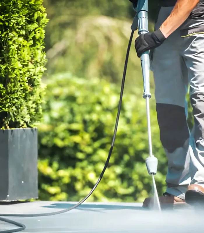 Mann wäscht mit Hochdruck Veranda vor einem Garten in Ludwigslust