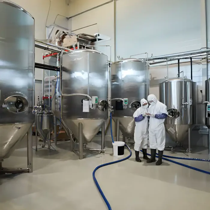 Zwei Arbeiter in Schutzanzügen inspizieren die Ausrüstung einer Brauerei in Recklinghausen