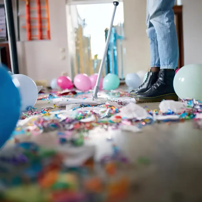 Person, die mit einem Mopp Konfetti und Luftballons vom Boden aufsammelt in Coswig