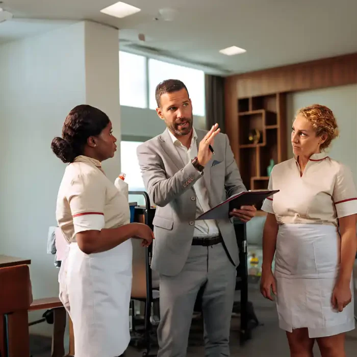 Ein Manager im Anzug im Gespräch mit zwei Hausangestellten in einem Hotel