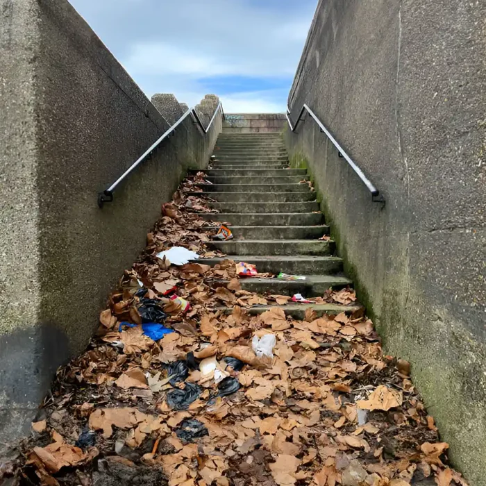Eine Betontreppe, bedeckt mit herabgefallenen Blättern und verstreutem Müll in Reutlingen