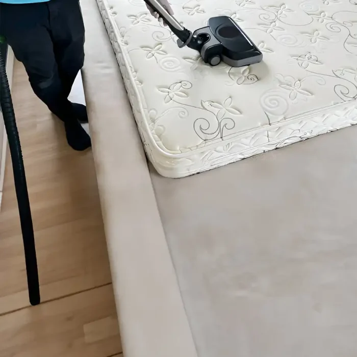 Person, die einen Staubsauger auf einer dekorativen Matratze in einem Schlafzimmer benutzt in Coburg