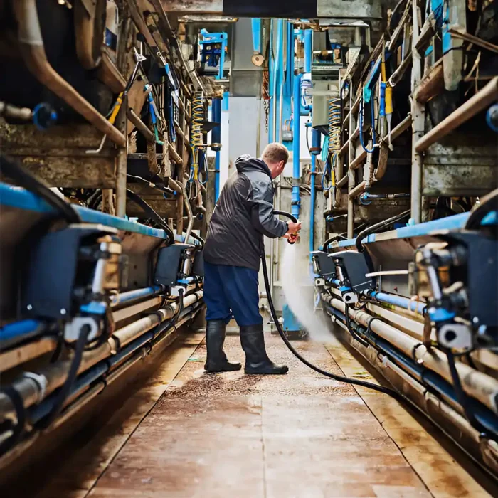 Ein Arbeiter reinigt mit einem Schlauch Maschinen in einer industriellen Produktionslinie in Recklinghausen