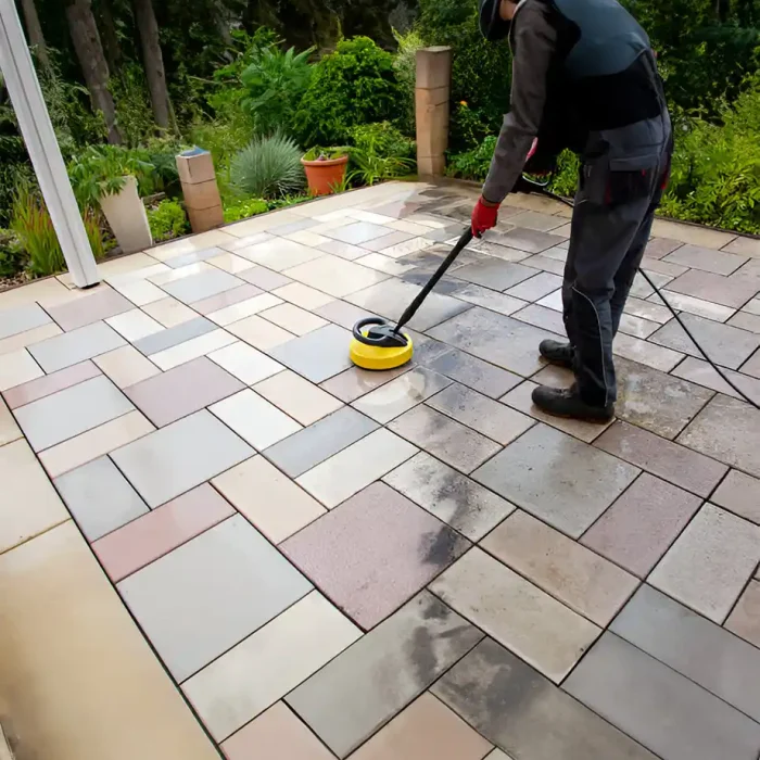 Arbeiter verwendet einen Oberflächenreiniger, um eine geflieste Terrasse mit verschiedenen Farbtönen zu reinigen