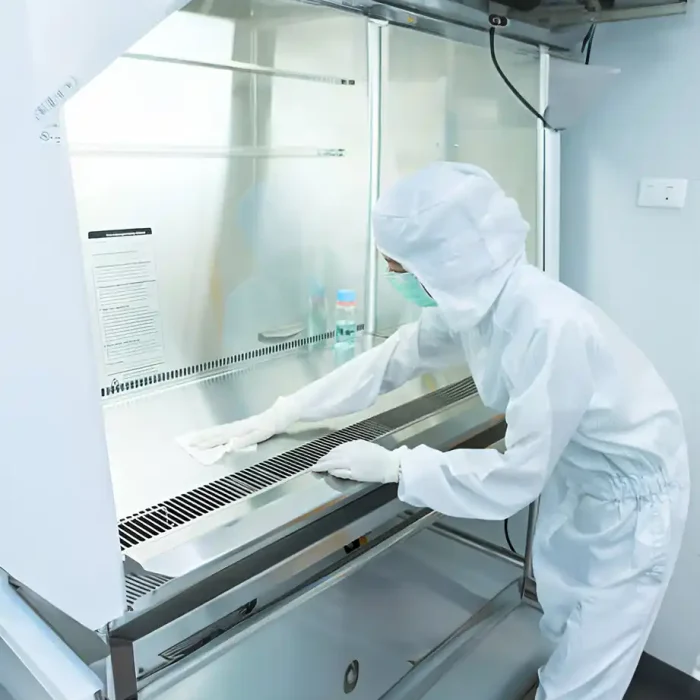 Person in Schutzkleidung beim Abwischen einer Laborfläche