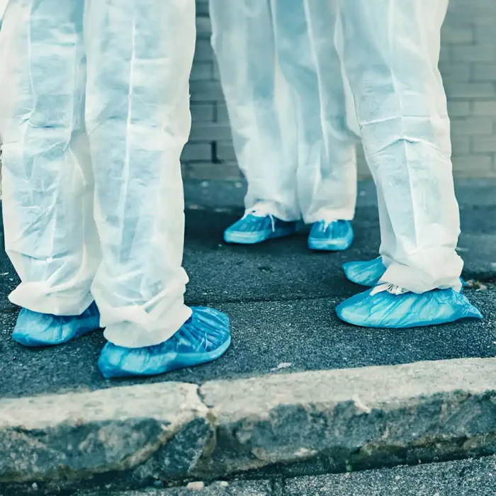 Aufnahme von Personen mit blauen Schuhüberziehern auf dem Bürgersteig