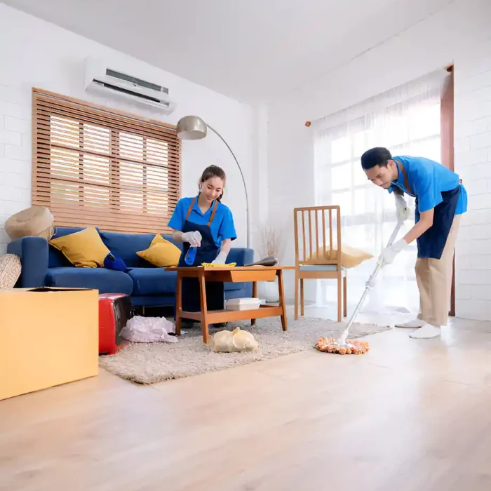 Zwei Personen in blauen Uniformen beim Aufräumen eines Wohnzimmers mit einem Sofa und einem Holzboden in Lampertheim