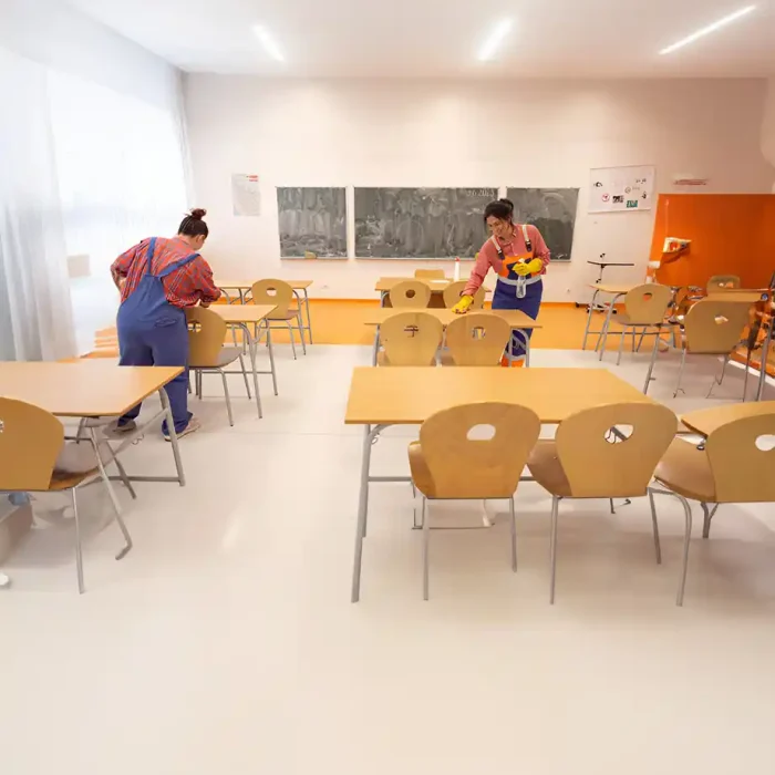 Zwei Arbeiter wischen die Tische in einem hellen Klassenzimmer ab in Reutlingen