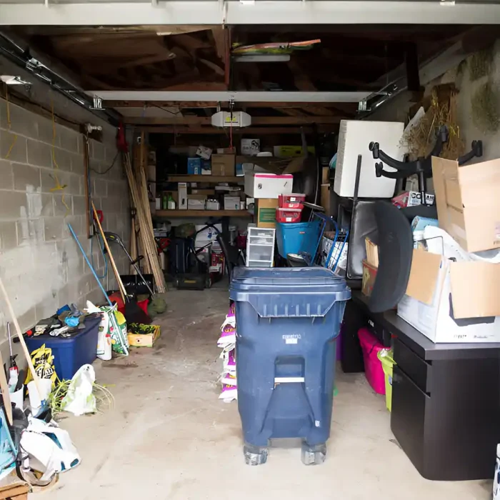 Garage gefüllt mit verschiedenen Gegenständen und einem blauen Mülleimer am Eingang