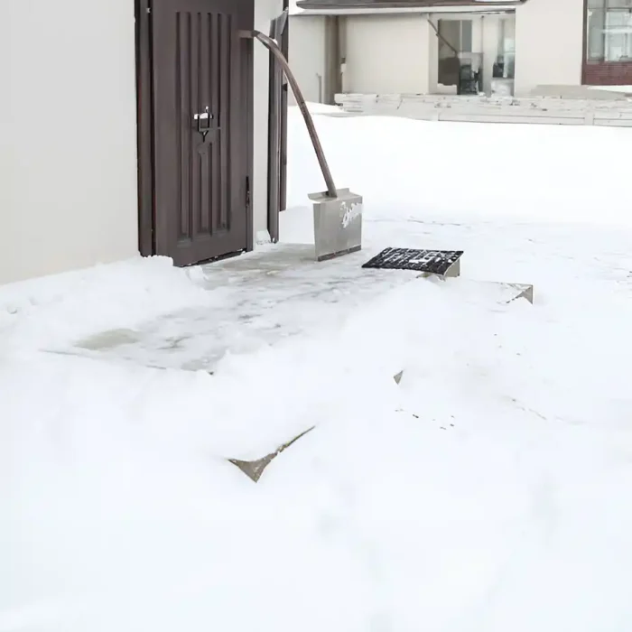 Schneeschaufel vor einer verschneiten Türschwelle
