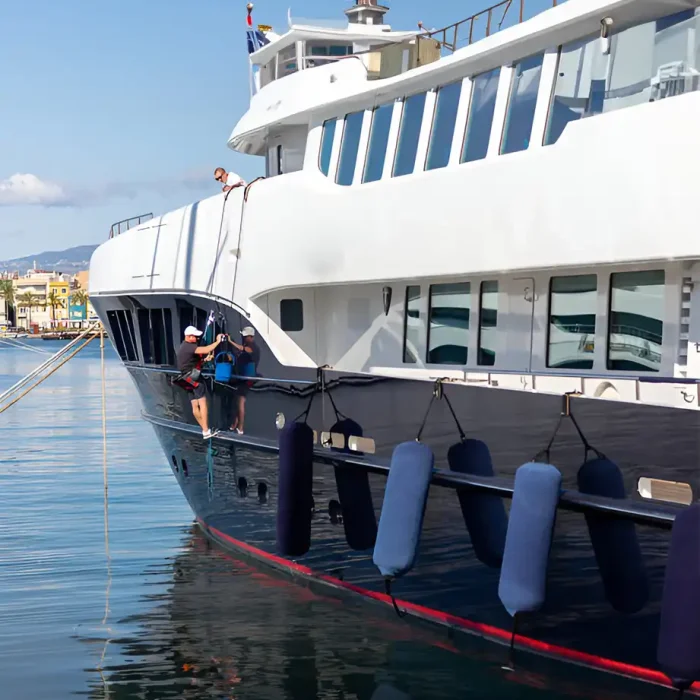 Arbeiter bei der Wartung einer großen Yacht, die in einem Hafen angedockt ist