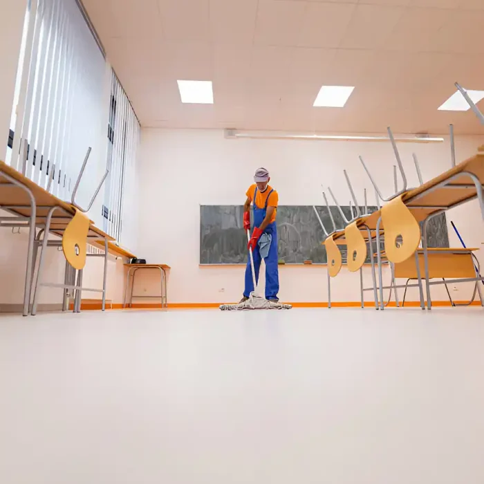 Hausmeister wischt den Boden in einem leeren Klassenzimmer, in dem die Stühle auf den Tischen gestapelt sind in Reutlingen
