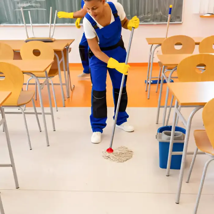 Arbeiter wischt den Boden eines Klassenzimmers, in dem die Tische und Stühle ordentlich angeordnet sind in Reutlingen
